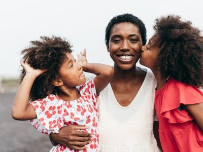 African sisters twins playing on the beach with smiling mother - Focus on mom face