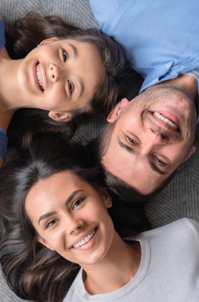 Happy family concept. Top view of happy family of three bonding to each other and smiling